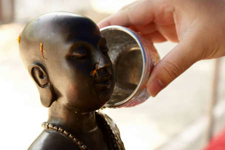 Pour water to Buddha imageの写真素材