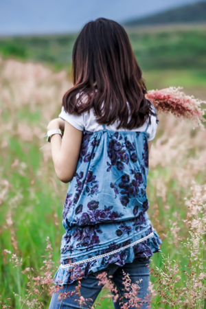 back of women stand among  flowering grassの写真素材