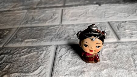 A cute small figurine of a himalayan child on a white brick backgroundの写真素材