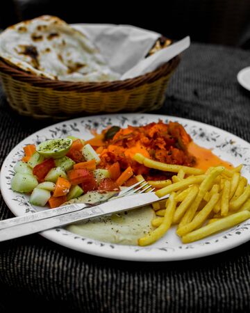 The Shakshuka delicacy of poached eggs, tomato sauces with fries, naan and veggiesの写真素材