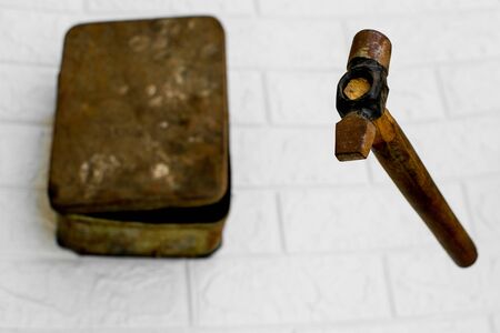Levitating rusty hammer with main focus on striking end and an old toolkit in faded backgroundの写真素材