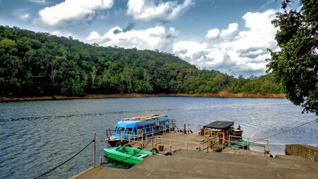 Landscape view of a couple of boats in a serene lake surrounded by forested hills and a cloudy skyの写真素材