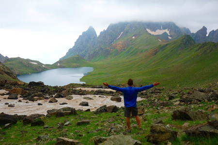 Young man after crossing a snowy mountain pass leading to Tobavarchkhili lake in Caucasus Mountains
