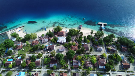 Aerial drone photo of Manggara Island in Raja Ampat, showing clear sea, coral reef, and untouched tropical nature in West Papua, Indonesia.の写真素材