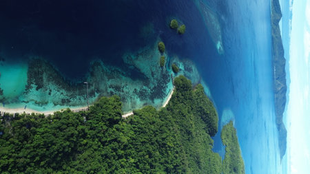 Aerial drone photo of Beser Bay in Raja Ampat, showing clear turquoise water, coral reefs, and lush tropical coastline in West Papua, Indonesia.の写真素材