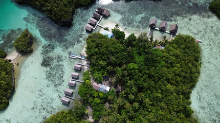 Aerial view of Beser Bay on Gam Island, Raja Ampat, showcasing vibrant coral reefs, turquoise waters, and the channel cutting through this marine biodiversity hotspot.の写真素材