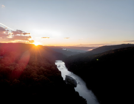 Majestic golden hour view of a tranquil river flowing through a lush mountain valley at dusk.の素材
