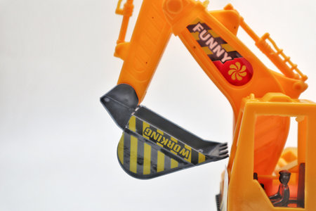 Clean side view of a toy excavator with caterpillar tracks, photographed on white background. A colorful and detailed childrens toy used for play or learning.の写真素材
