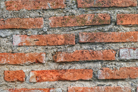 Detailed view of an old red brick wall showing rough textures, weathering, and mortar patterns.の写真素材