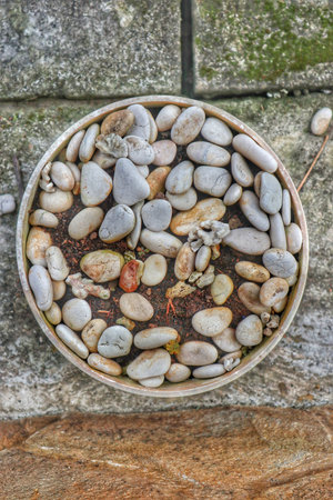 A rustic clay pot filled with smooth stone pebbles, creating a serene and natural composition.の写真素材