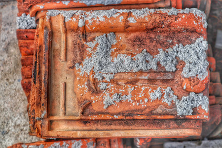 Macro shot of a single used clay roof tile, highlighting its texture, earthy tone, and weathered...