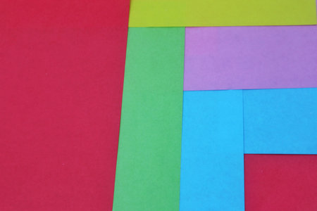 An abstract symmetrical composition of red, blue, purple, green, and yellow colored paper, with red...