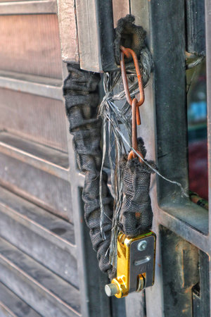 A close-up of a sturdy metal chain wrapped around a padlock, resting on a textured, possibly weathered, surface, symbolizing security or restriction.の写真素材