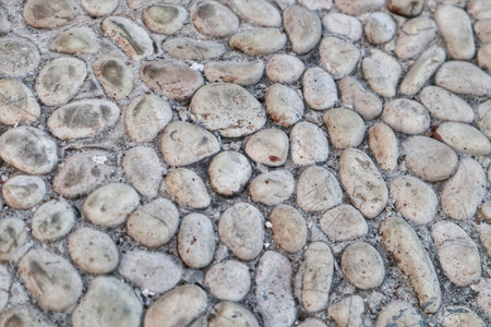 A rustic and organic background featuring a wall made of natural, irregularly shaped stones, showcasing varying tones and rough textures, ideal for earthy designs.の写真素材