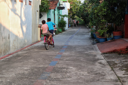 Two children in a village street, actively engaged in learning or practicing how to ride their bicycles, capturing a moment of development and outdoor play.の写真素材