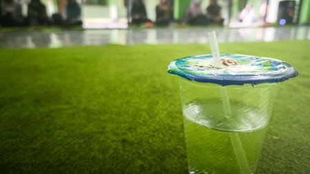 Refreshing Green Drink in Plastic Cup on Indoor Green Carpet During a Casual Gathering