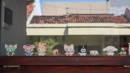 Colorful block figures displayed on a wooden windowsill overlooking an urban landscape