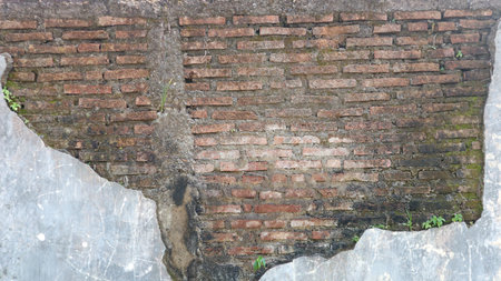 Weathered Exterior Wall with Peeling Plaster Revealing Old Brickwork Texture