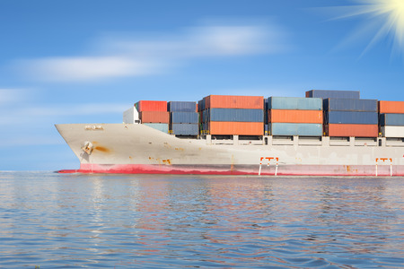 Cargo ship and cargo container in sea with clear sky background.