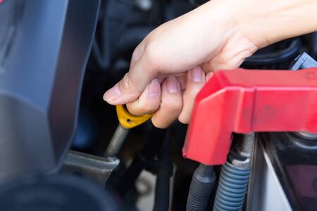 Asian woman's hand checking level of lubricant oil of car engine.の写真素材