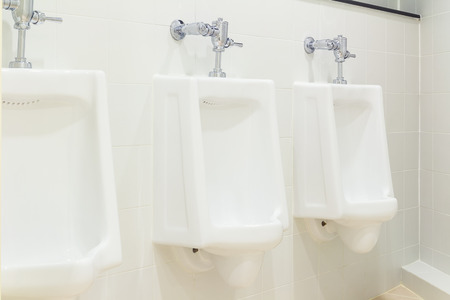 Row of white urinal for men on tile wall in toilet.の写真素材