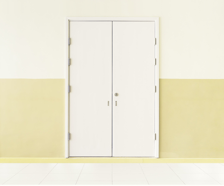 Wood door and white tile floor inside office building.の写真素材