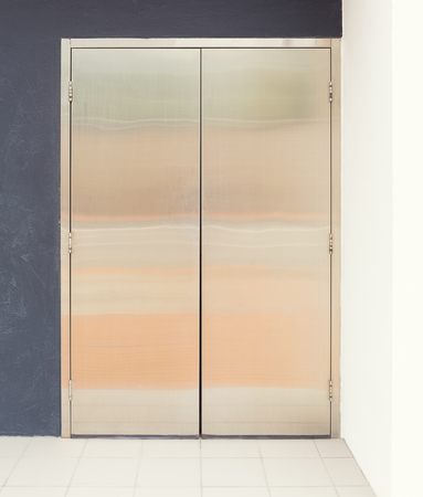 Stainless steel door and white tile floor outside office building.