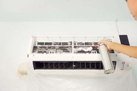 Woman cleaning air conditioner by foam cleaning agent.の写真素材