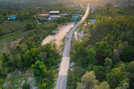 Aerial view of rural road cross green forest and sunlight evening time in Baan mai takian, Lamphun of Thailand.の写真素材