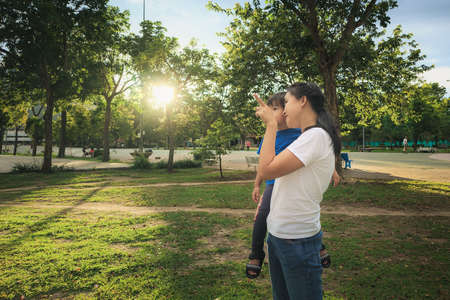 Mother play with her son against with nature and sunlight background.の写真素材