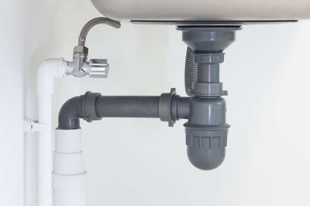 Drain pipe or sewer under kitchen sink. Pvc plastic pipe and
 flexible supply tube connection to...