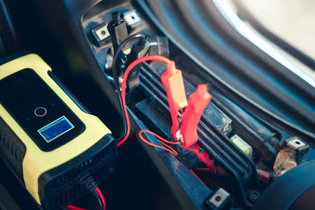 Charging electric power, energy to accumulator or dead battery in breakdown motorcycle for start. Include equipment tool i.e. portable trickle charger, positive negative clamp, red black cable wire.の写真素材