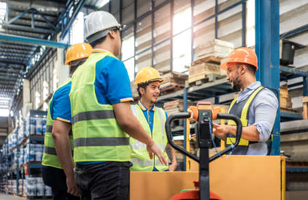 Manager, staff or boss to talking, discussion with worker, employee. Group of people in warehouse, factory with safety helmet, vest. Concept for industry, job, meeting, work trainiの写真素材