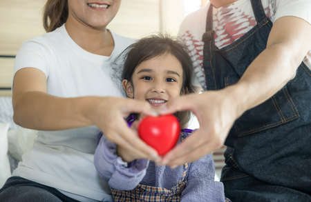 Portrait of daughter, parent or father, mother in bedroom or home. 3 people to smile and hold heart...