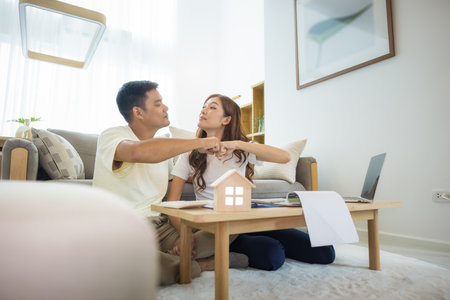 Asian couple in home or house. To compare prices, interest, credit. Include laptop, calculator and document on table. Concept for marriage, loan, real estate, property.の写真素材