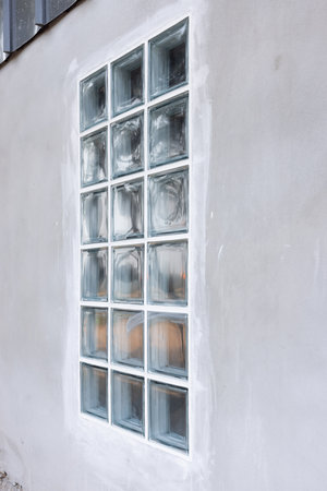 Building exterior in perspective view with transparent glass block on concrete wall under...