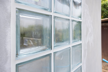 Close up transparent clear glass block in perspective on concrete wall under construction. Apply...