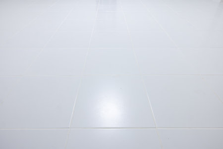 White tile floor with grid line of square texture pattern in perspective at night. Clean shiny of ceramic surface. Modern interior home design. Empty space for background.の写真素材
