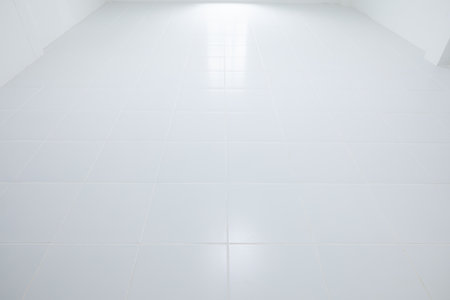 White tile floor with grid line of square texture pattern in perspective at day. Reflection with warm white light. Clean shiny of ceramic surface. Interior home suit for backgroundの写真素材