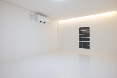 Empty room with square white tile floor texture pattern in perspective at night. Include glass block wall, air conditioner and hidden strip light on ceiling suit for background.の写真素材