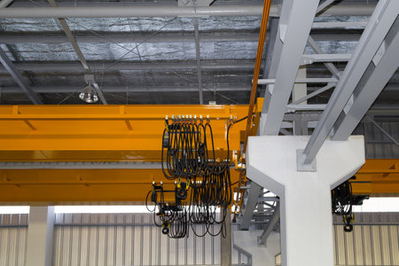 Overhead crane in factory or warehouse. Industrial machine or lifting equipment with hoist, hook on beam girder for manufacturing production and freight shipping transport.の写真素材