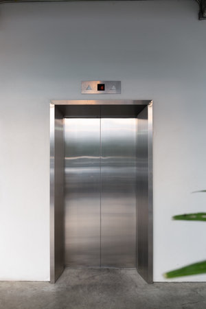 Elevator front door. Glossy stainless steel surface and clean concrete floor in front. Modern design...