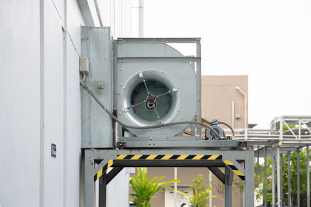 Industrial blower unit mounted outdoors on exterior building wall, part of ventilation system and...