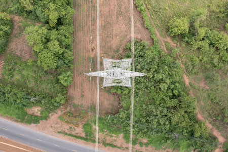 Aerial view of power lines stretching across lush green landscape, highlighting energy infrastructure. Represents electricity transmission, sustainable power supply.の写真素材
