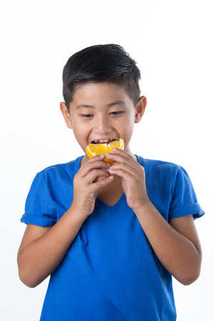 Child with oranges. Happy little boy with fruit on white backgroundの写真素材