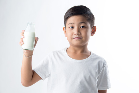 Portrait of a cute schoolboy with a glass of milk, on white backgroundの写真素材
