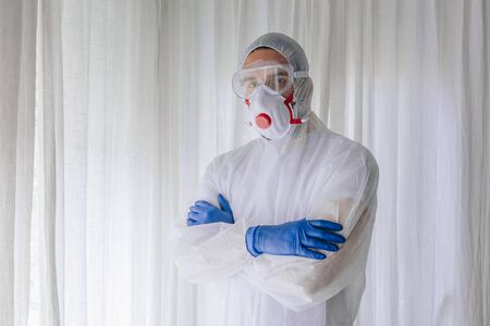 Doctor in protective suit and face mask with arms crossedの写真素材