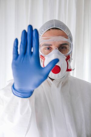 Doctor in protective suit and face mask making stop gesture stock photoの写真素材