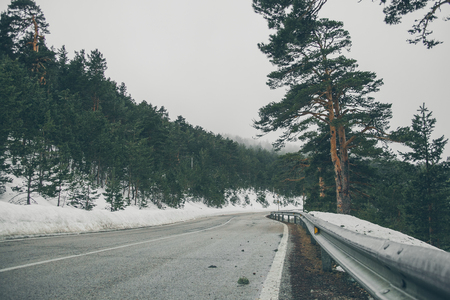 High mountain road. Mountain landscape with snow. Road trip trough the mountains. Road in the forest. View of the mountain road in Navacerrada.の写真素材