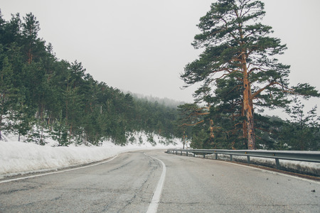 High mountain road. Mountain landscape with snow. Road trip trough the mountains. Road in the forest. View of the mountain road in Navacerrada.の写真素材